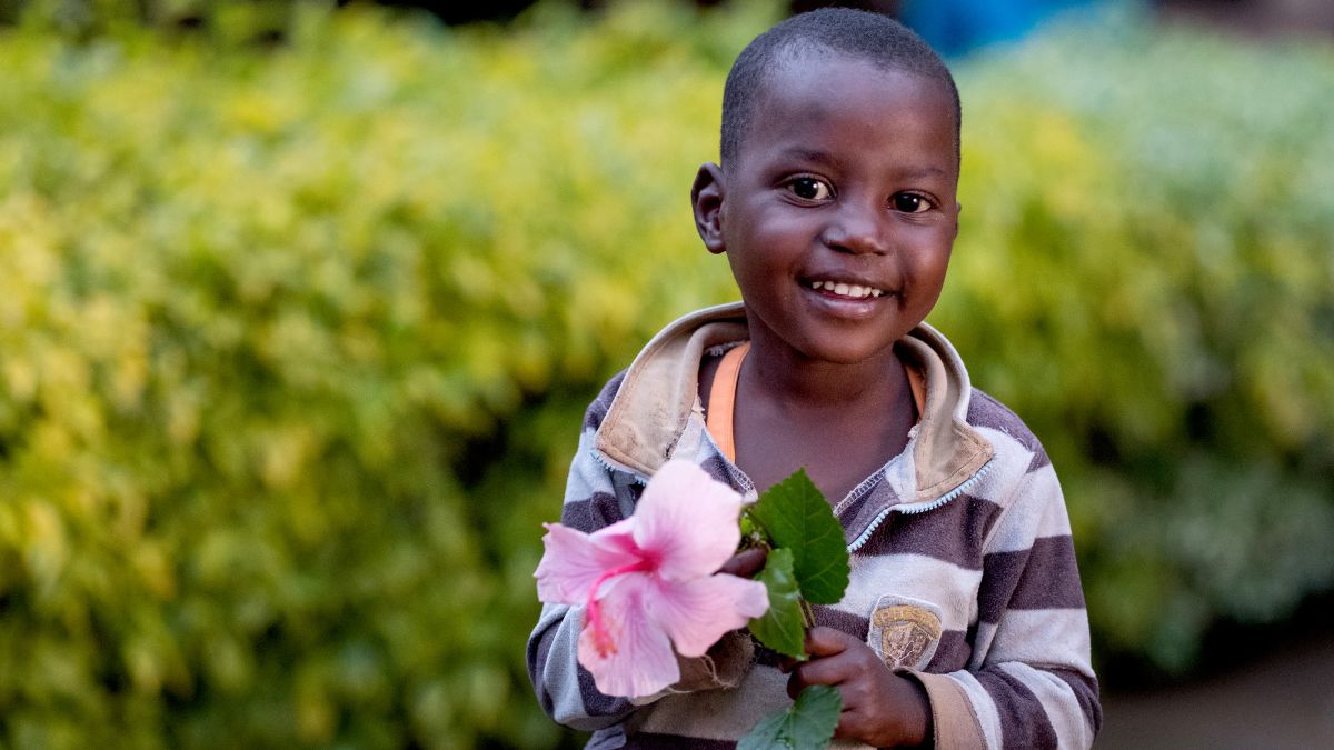 Ein kleines afrikanisches mädchen mit einer Blume in der Hand.