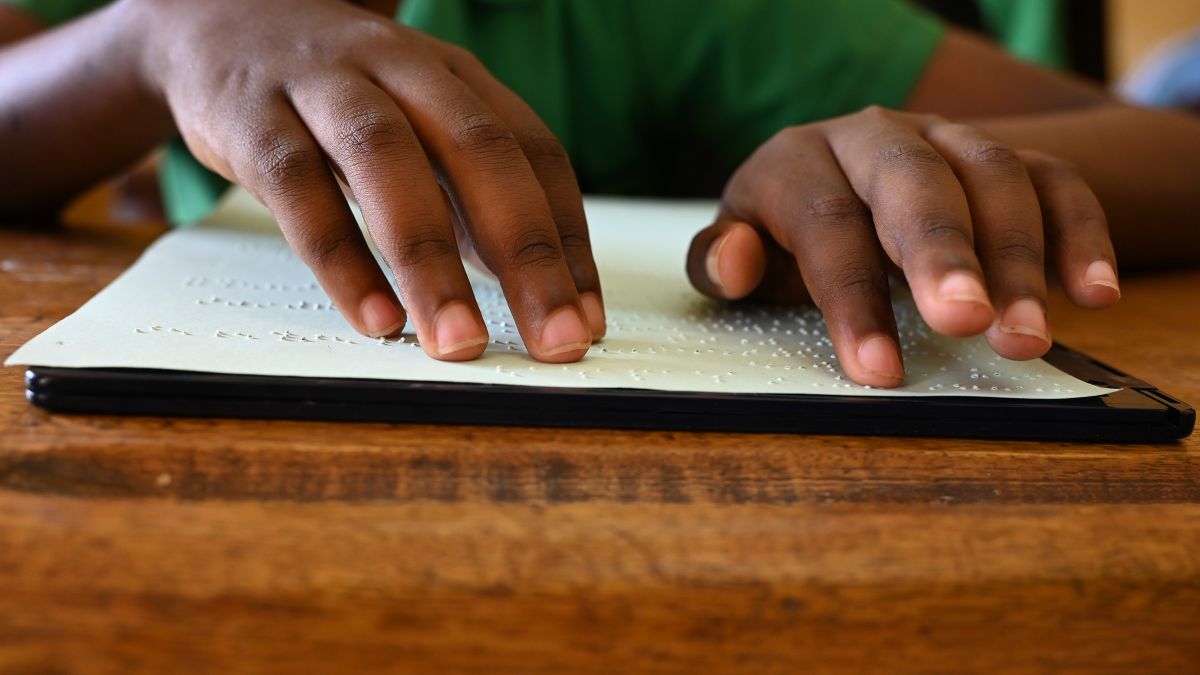 Hände fahren lesend über eine Braille-Tafel.