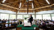 Ein Mann steht mit Mikrofon in einer Kirche hinter dem Altar. Finden Sie zahlreiche Ideen und Vorlagn für Ihren Gottesdienst.