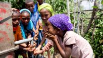 Afrikanische Schüler*innen waschen sich an einer Wasserpumpe das Gesicht