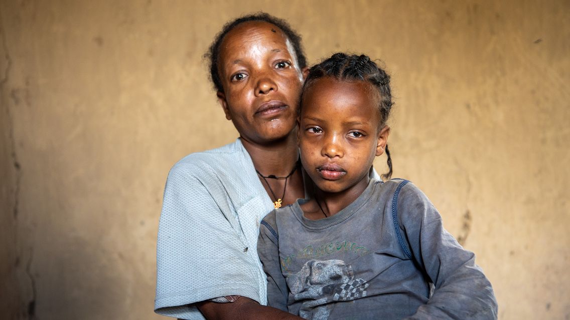 Eine Frau legt die Arme um ein etwa fünfjähriges Mädchen.