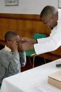 Afrikanischer Junge, dem jemand eine Brille aufsetzt.