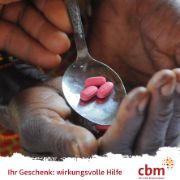 Eine Hand hält einen Löffel, auf dem drei Tabletten liegen