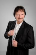 Mann in Jackett und weißem Hemd, dessen Knopfleiste mit Musiknoten bestickt ist