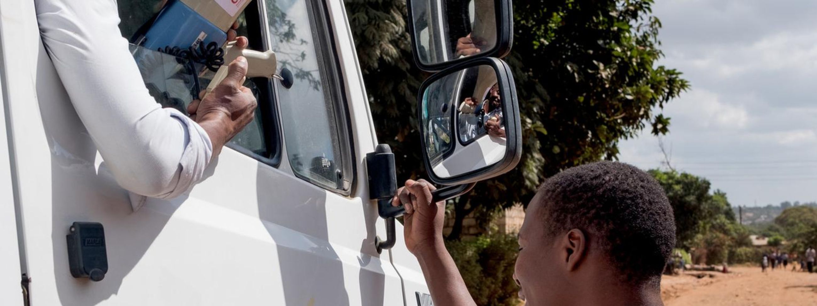 Aus dem Autofenster herausschauender afrikanischer Mann mit Megaphon