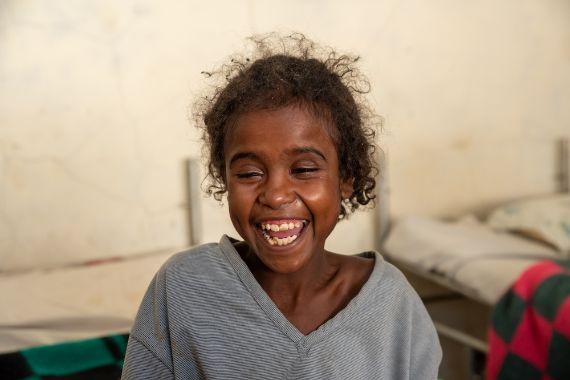 Etwa neujähriges, lachendes Mädchen.