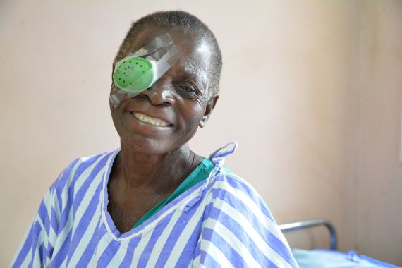 Eine ugandische Frau mit Augenklappe sitzt im Krankenhausbett