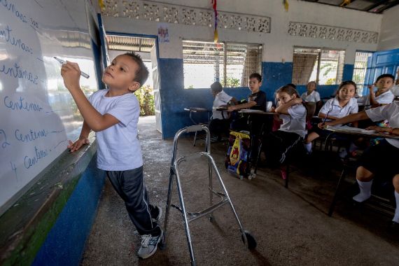 Ein körperbehinderter Junge lehnt an einer Schultafel und schreibt / Nicaragua